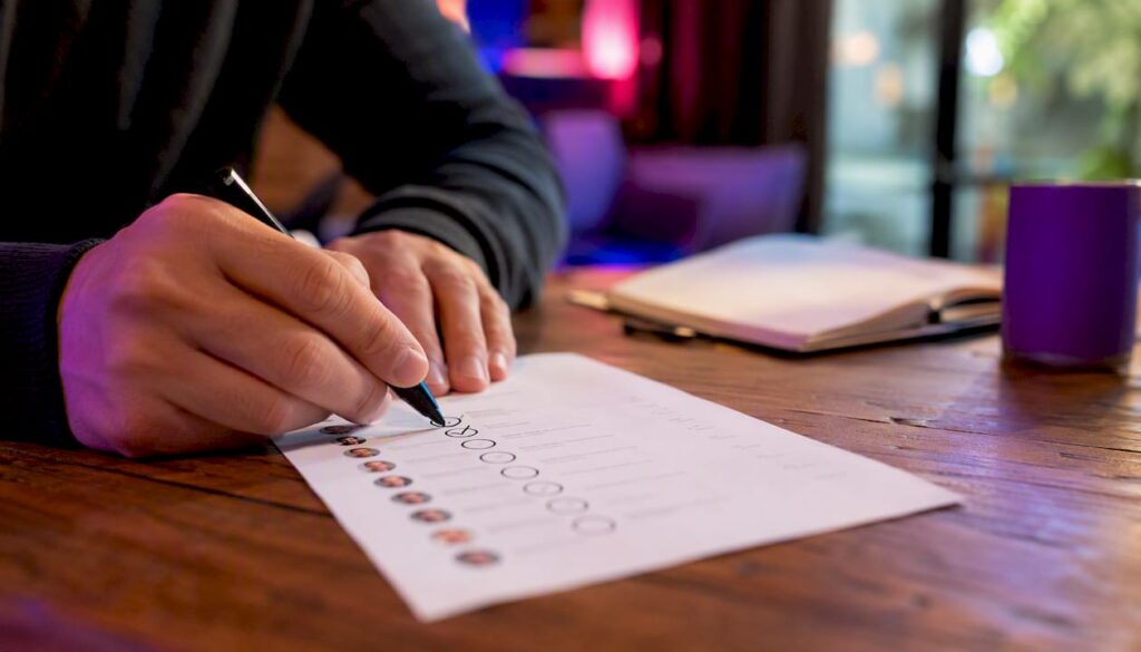 Des mains attribuent des scores à des prospects B2B sur une liste papier.