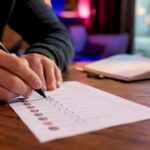 Des mains attribuent des scores à des prospects B2B sur une liste papier.